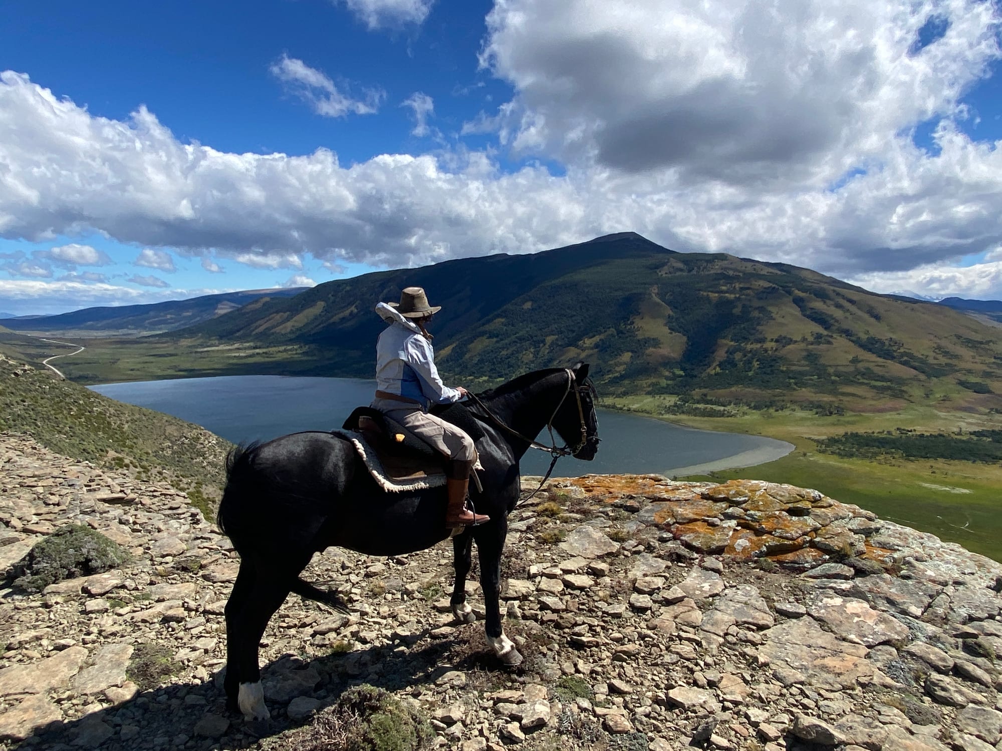 A rider on a black horse at a ridge above Laguna Figueroa